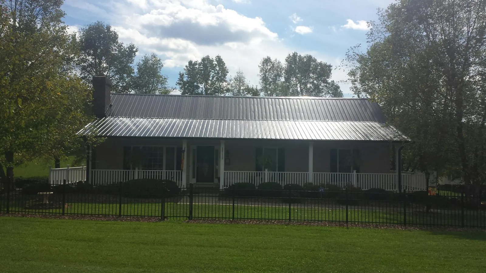 Gray metal roof on a brick ranch with a full width front porch — Gutter Guard Installation work by our crew in Rolling Prairie