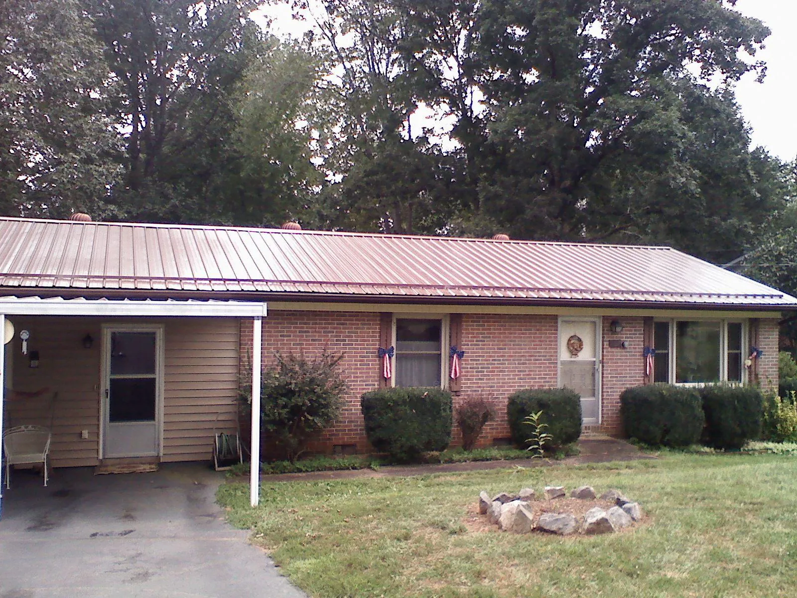 Bronze metal roof and carport on a brick ranch home — Roof Repair work by our crew in Rolling Prairie