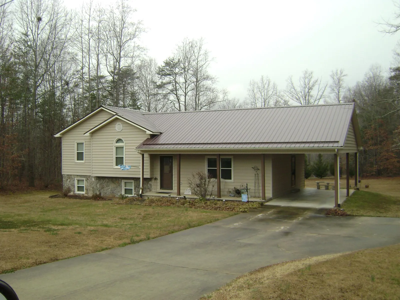 Brown metal roof on a tan split level home with an attached carport in Rolling Prairie