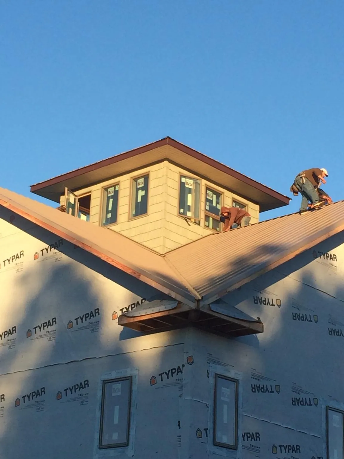 Roofers working around a rooftop cupola on a new metal roof at sunset — Roof Waterproofing in Rolling Prairie by Roofing Brothers